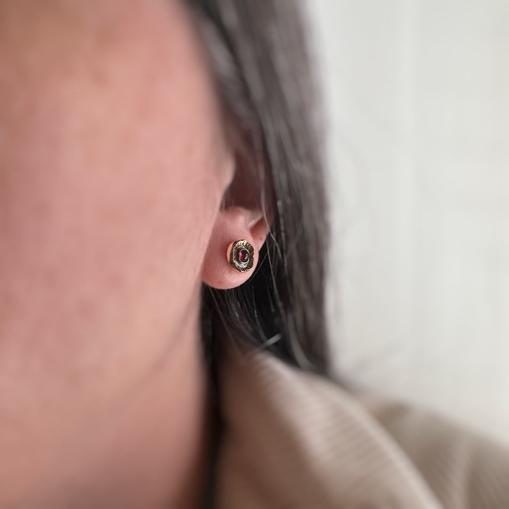Handmade brass flowers with small round garnets set in the center. Surgical steel post earrings, shown on model.