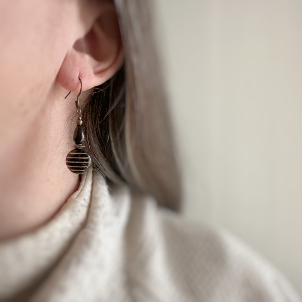dangle earrings with a black and gold striped coin shaped bead, bronze ear wires