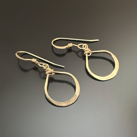 Gold teardrop earrings on a dark gray background