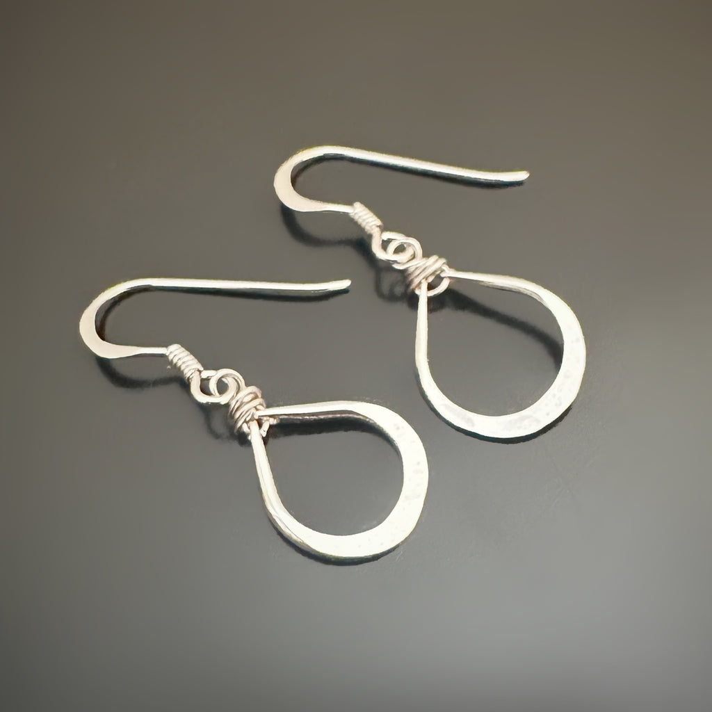 Pair of hand hammered silver teardrop earrings on a dark gray background