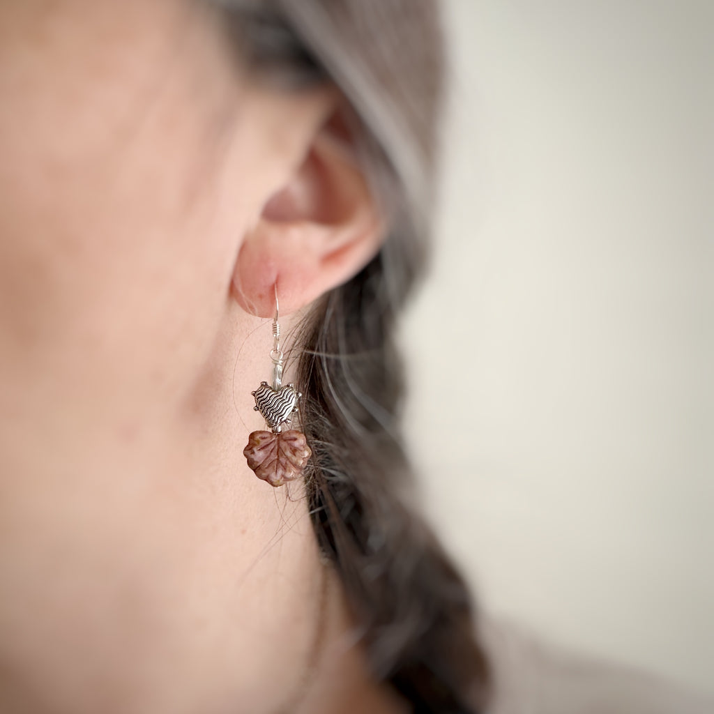 Leaf and heart earrings in coral on model.