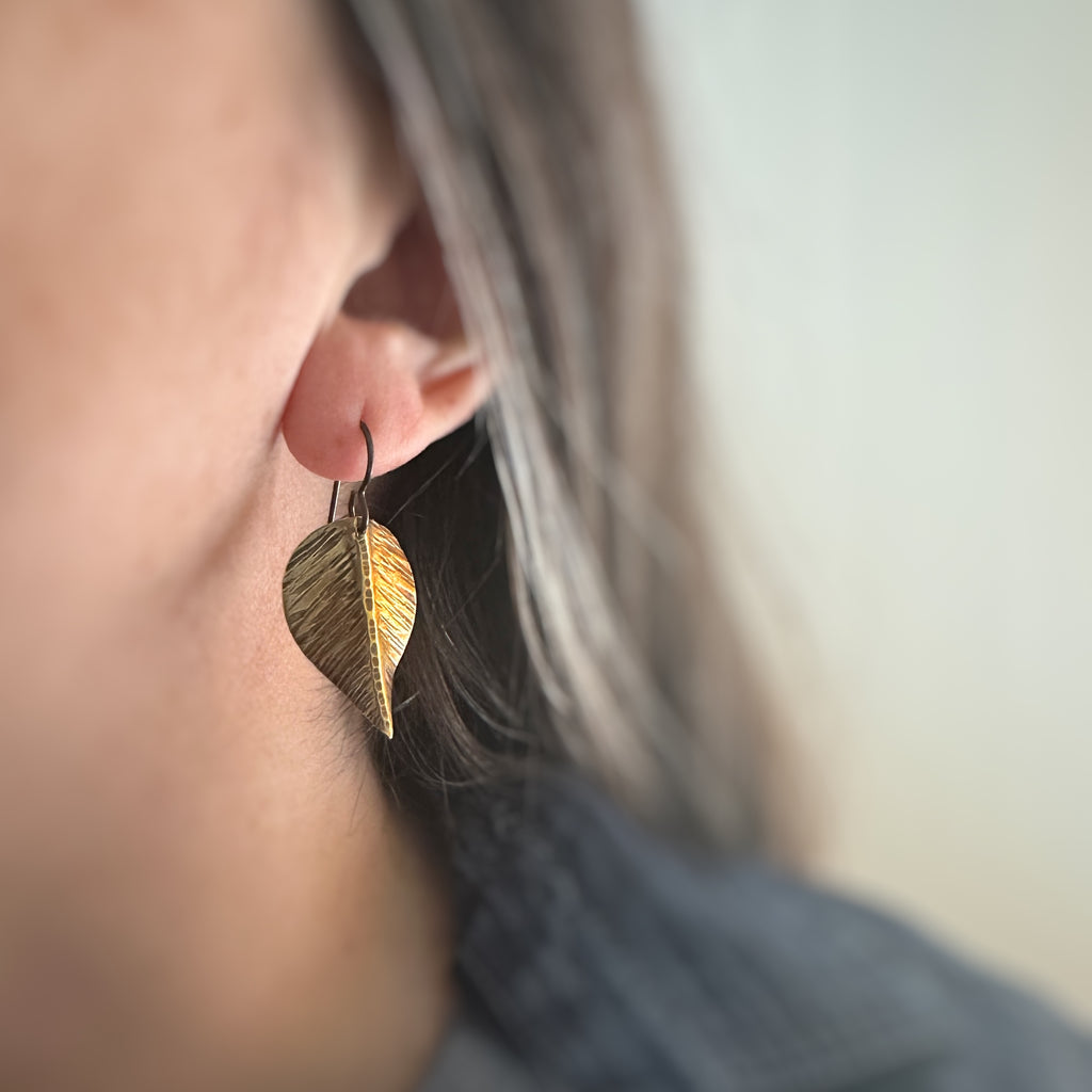 large earrings that are hand formed and hammer textured leaves made of oxidized brass