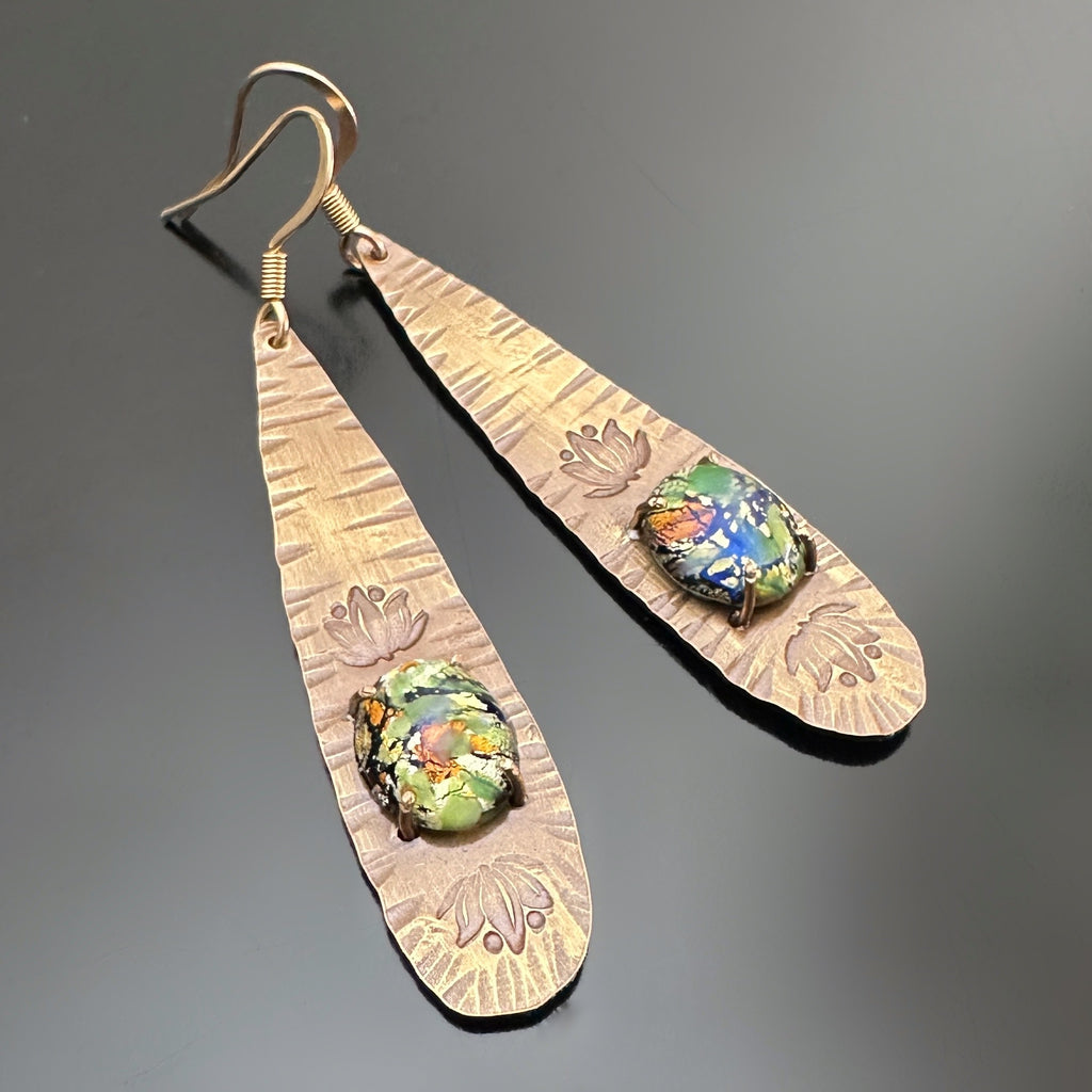 long brass teardrop earrings with french hook ear wires. The tear drop has hammer marks and stamped lotus flowers with a focal of a green opal glass oval, prong-set near the bottom.