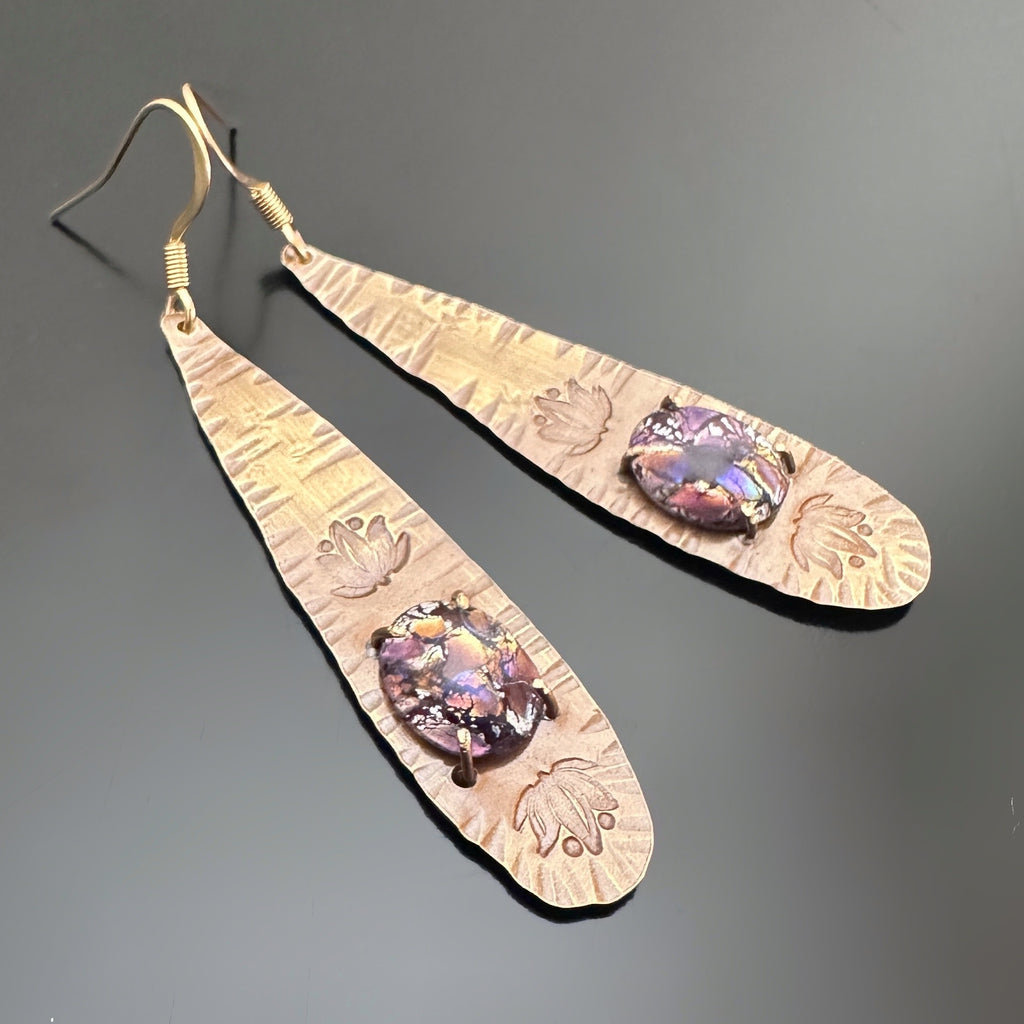 long brass teardrop earrings with french hook ear wires. The tear drop has hammer marks and stamped lotus flowers with a focal of a light purple opal glass oval, prong-set near the bottom.