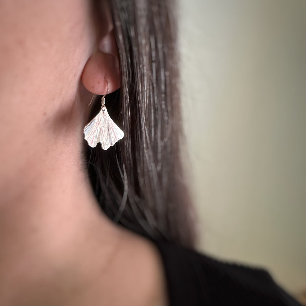 Medium sterling silver ginkgo leaf earrings on model.