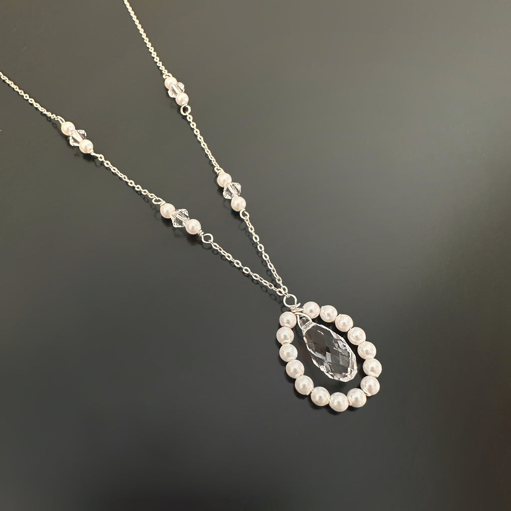 Sterling silver with a pendant featuring a beaded teardrop of white pearls and a clear teardrop crystal.  The chain has pearls and crystal interspersed within.