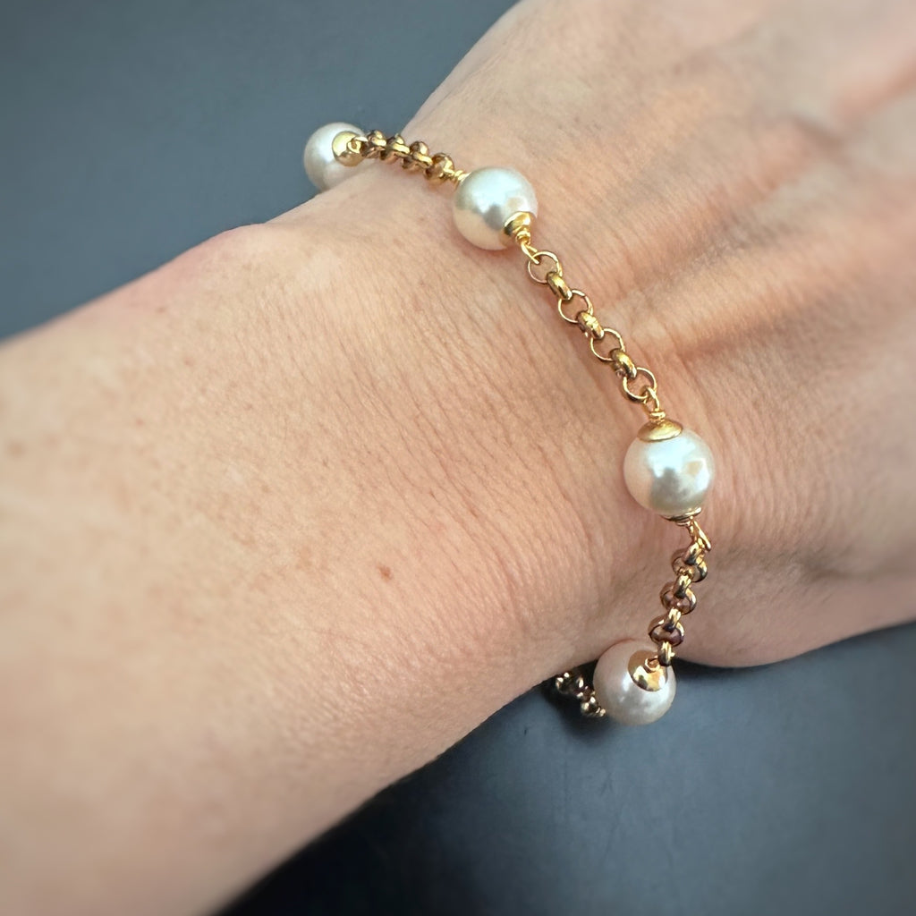 8mm white crystal pearls are stationed evenly throughout a gold tone heavy rolo style chain. shown as worn