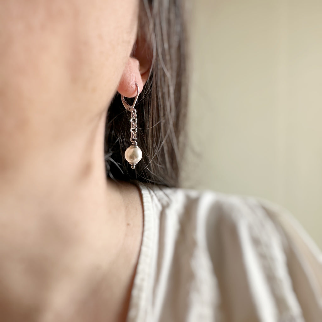 1.5 inches long earrings with lever-back style ear wires, they have an 8mm round, white crystal pearl dangling from a silver rolo chain.