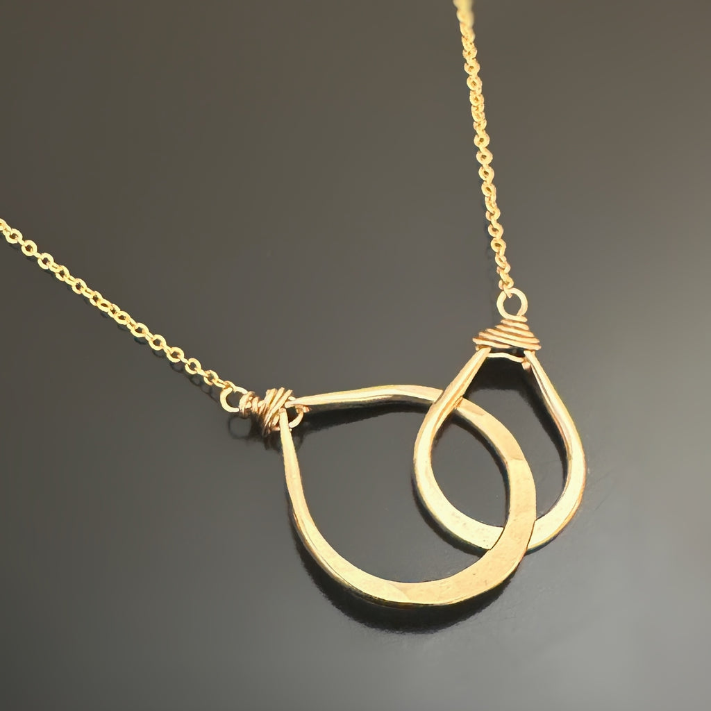 14k Gold-filled necklace with double teardrops of two different sizes interlocking pendant on a dark background