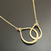 14k Gold-filled necklace with double teardrops of two different sizes interlocking pendant on a dark background