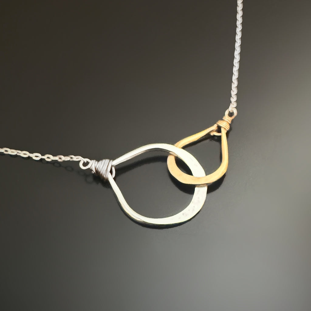 This necklace features two handmade interlocking teardrops.  One is sterling silver the smaller on is 14k gold-filled.  The teardrops are attached to an adjustable length sterling silver chain.