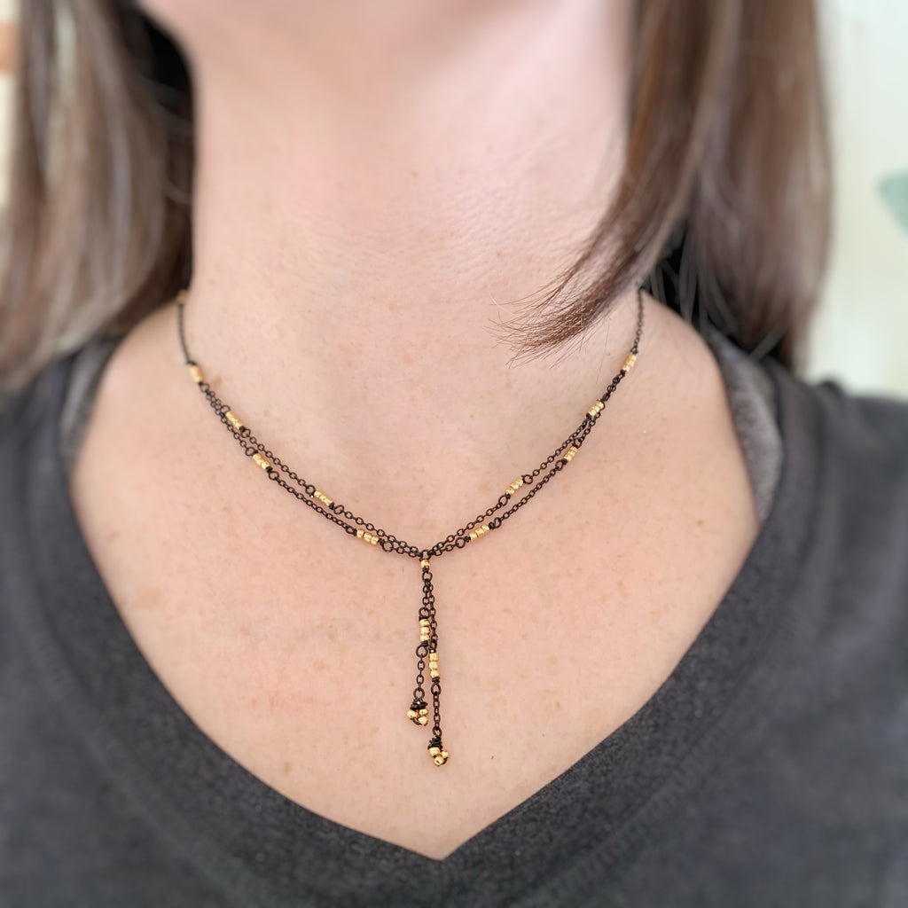 lace like y shaped necklace with black chain and golden beads
