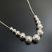 Sterling silver necklace with round beads in graduated sizes on chain.