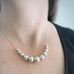 Sterling silver graduated size beaded necklace with chain shown on model.