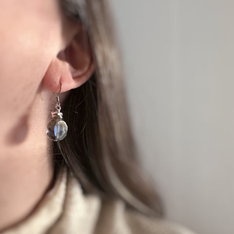 Earthy blue, transparent glass faceted nugget drop earrings with silvery accents and surgical steel ear wires. Shown on model.