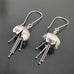 Hand made and scuplted surgical grade steel inverted flower pendant with a satin finish with  long dangling stamen. Hanging from a long shepherds hook ear wires.