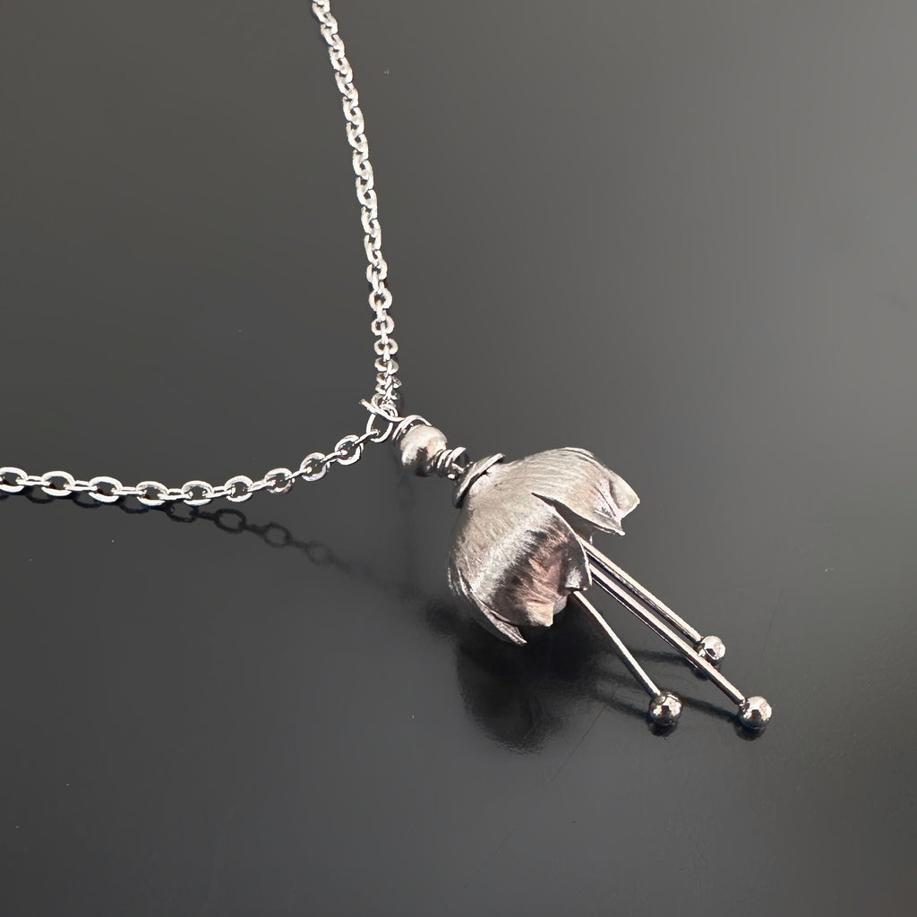 Hand made and scuplted surgical grade steel flower with a satin finish. The pendant hangs from a delicate chain. 
