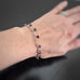 faceted cube shaped garnet beads dangling from a paper clip style silver tone chain. Shown on model.