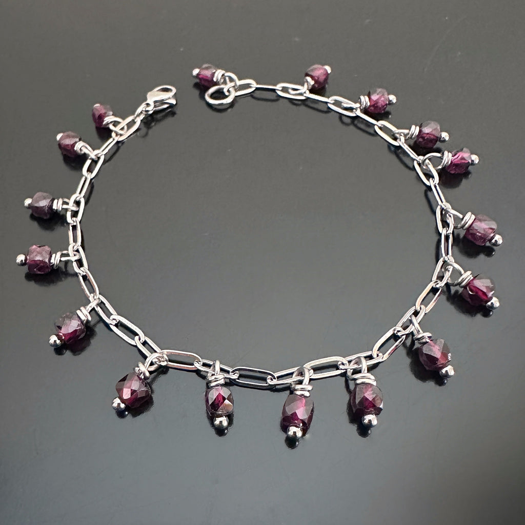faceted cube shaped garnet beads dangling from a paper clip style silver tone chain.