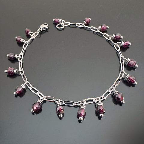 faceted cube shaped garnet beads dangling from a paper clip style silver tone chain.