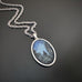 Silver color oval shaped pendant, hand painted depicting Lightning Bugs in the Midnight Pines.