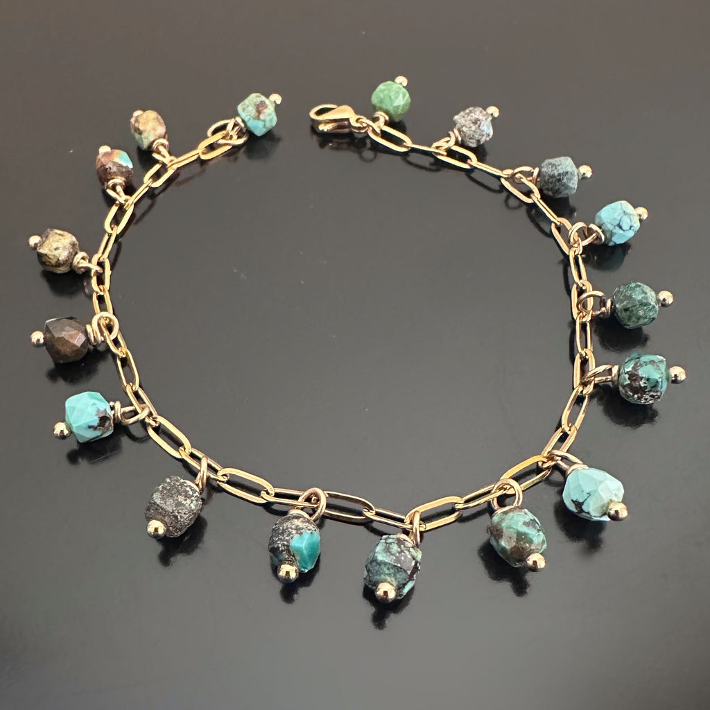 Faceted cube shaped turquoise beads, dangling like fringe off of a gold-tone paperclip style chain bracelet.