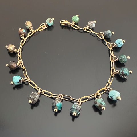 Faceted cube shaped turquoise beads, dangling like fringe off of a gold-tone paperclip style chain bracelet.