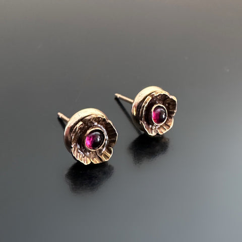 Handmade brass flowers with small round garnets set in the center. Surgical steel post earrings