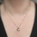 Gold tone necklace with flower shaped pendant that has a small moonstone set in the middle. Shown with 18 inch chain on model.