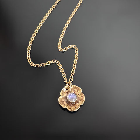 Gold tone necklace with flower shaped pendant that has a small moonstone set in the middle.
