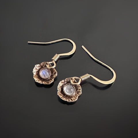 Tiny golden flower shape dangle earrings with moonstones set in the middle of each flower.