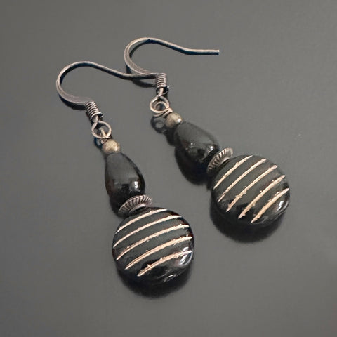 dangle earrings with a black and gold striped coin shaped bead