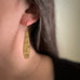 Brass teardrop earrings with stamped ginkgo leaves on model. 