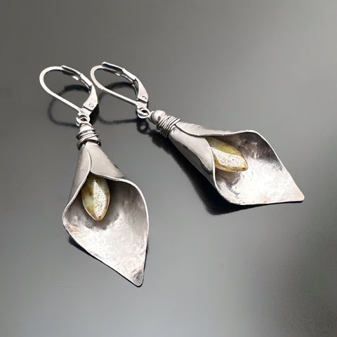 Hand formed silver tone surgical steel inverted calla lily drop earrings with pale green Czech glass stamen.  The earrings use lever-back style ear wires. 