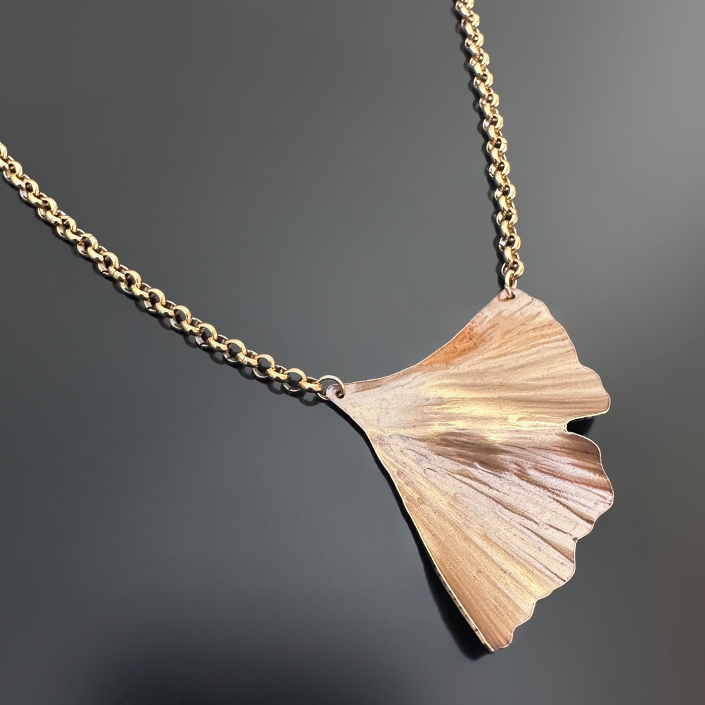 Golden oxidized brass necklace with a ginkgo leaf shaped pendant on a heavy rolo style chain