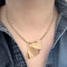 Golden oxidized brass ginkgo leaf necklace with heavy rolo style chain worn by a person.