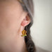 Flower stem earrings in amber color on model.