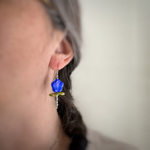 Flower stem earrings in blue on model.