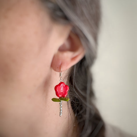 Red color flower stem earrings on model.