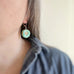 lever back style dangle earring with turquoise color glass coin shaped bead with crackled golden hearts in the center. 