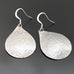 Large silvery teardrop dangle earrings with a subtle hammered texture.