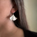 Large sterling silver ginkgo leaf earrings on model.