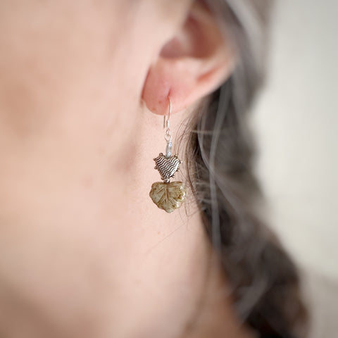leaf and heart earrings in light sage green on model.