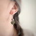Leaf and Heart earrings in sage green on model.