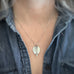 Large, silver leaf-shaped pendant on a delicate chain necklace show being worn.