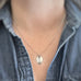 Small, silver leaf-shaped pendant on a delicate chain necklace show being worn.