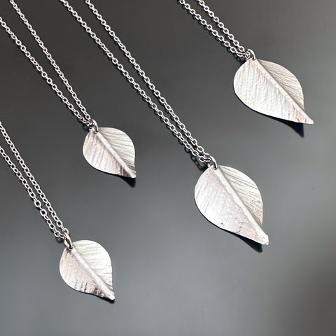 Silver toned surgical steel leaf necklaces on a delicate chain, showing 4 different size  options