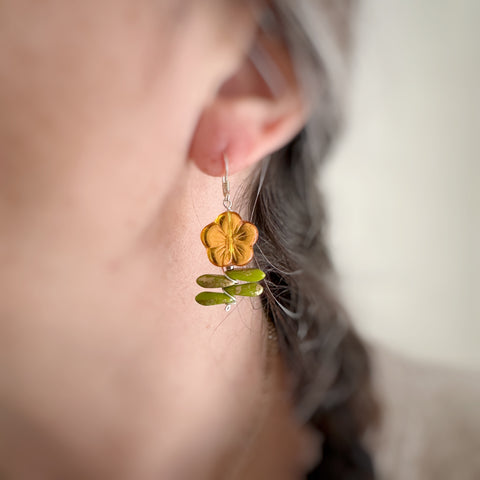 Leafy flower earrings in amber on model.