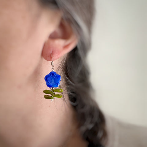 Leafy flower earrings in blue on model.