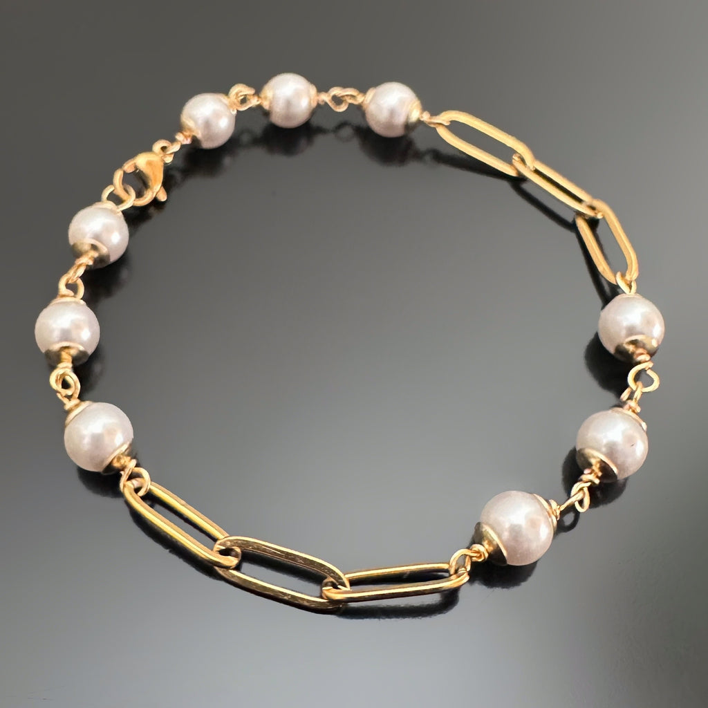 6mm white crystal pearls linked in groups of three interspersed within a gold tone paperclip style chain.